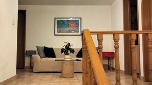 Ein Wohnzimmer mit einem beigen Sofa, einem kleinen runden Tisch und einer Holztreppe.