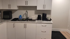 A compact kitchen with white cabinets, a sink, a coffee maker, and a toaster.