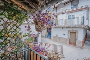 Un balcon orné de plantes en pot, un mur de pierre et une porte bleue.