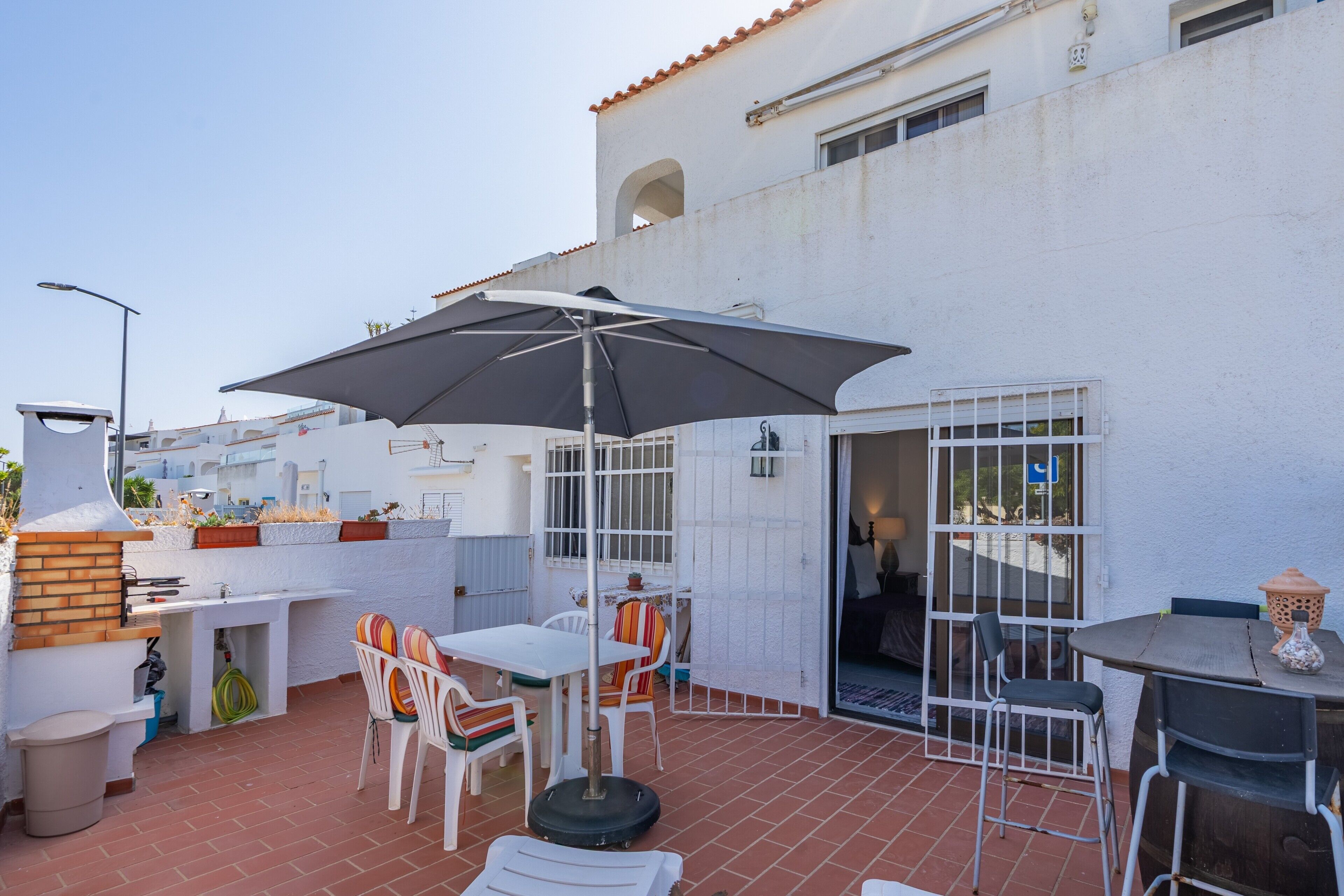 Eine Terrasse im Freien mit Tisch, Stühlen und einem großen Sonnenschirm.
