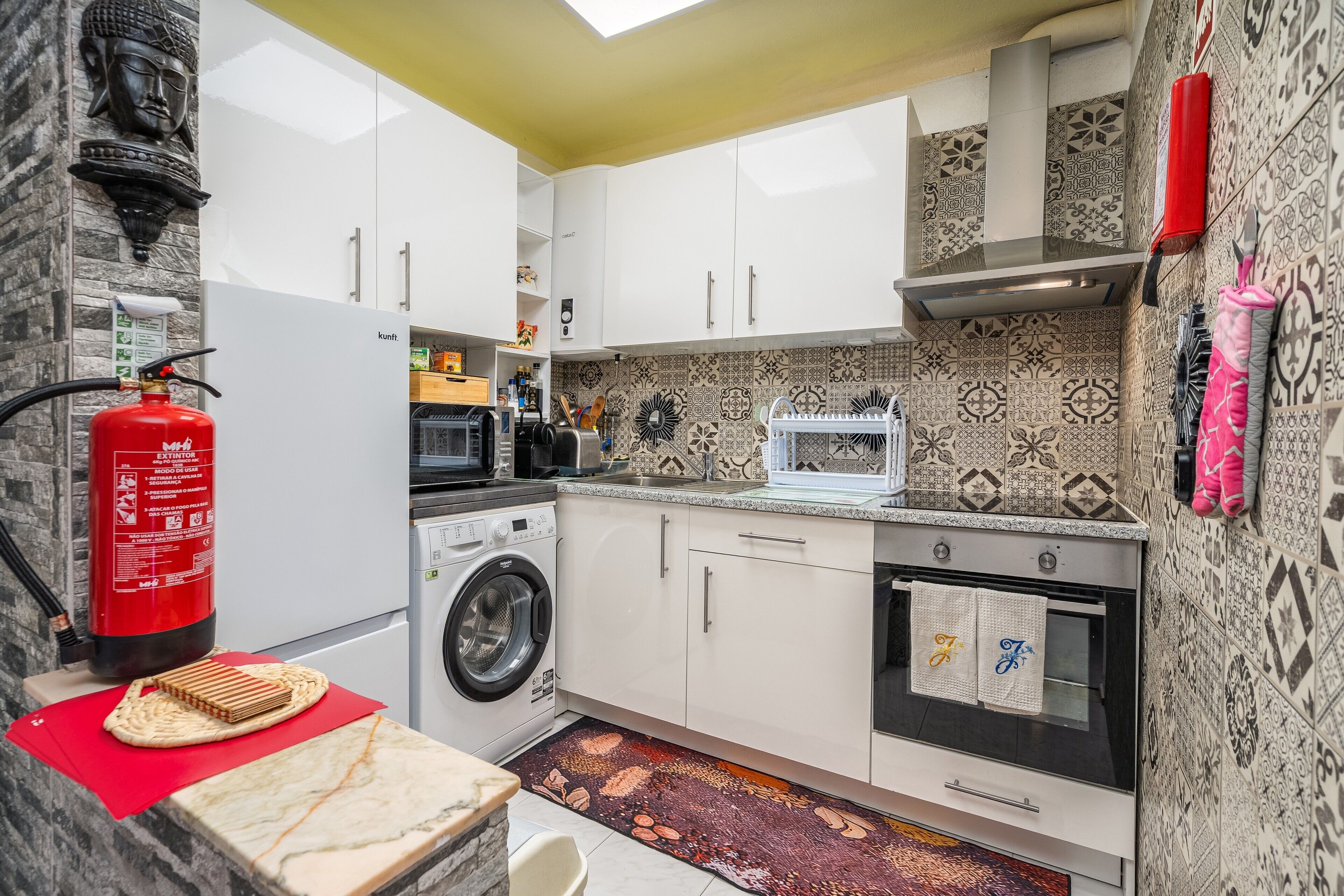 A modern kitchen with a washing machine, oven, and patterned backsplash.