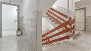 Un intérieur moderne avec un escalier en colimaçon, une plante en pot et une porte portant l’inscription « C ».