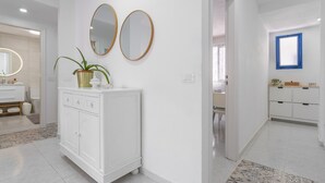 Une salle de bain moderne avec un meuble-lavabo blanc, deux miroirs et une plante en pot.