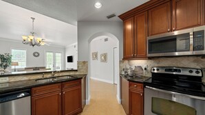 A modern kitchen with wooden cabinets, stainless steel appliances, and a central island. - Beautiful Condo Near Pool and Attractions (Kissimmee)