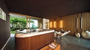 Un espace spa moderne avec un banc en bois, un jacuzzi et une vue sur la verdure environnante.
