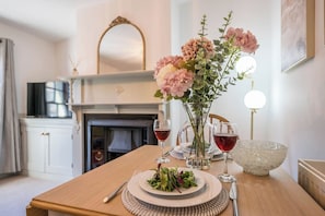 A dining table with a vase of flowers, two wine glasses, a bowl, and a plate of salad. - 3a Childs Yard, Southwold (Southwold)