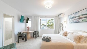 Ein Hotelzimmer mit Bett, Schreibtisch, Stuhl, Fenster mit Blick und einem Gemälde an der Wand.