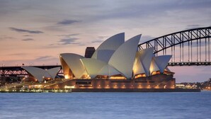The Sydney Opera House with its distinctive sail-like design, located adjacent to the Sydney Harbour Bridge.