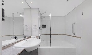 A modern bathroom with a large sink, a glass-enclosed shower, and a bathtub.