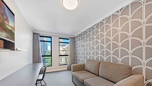 A modern room with a sofa, a dining table, and two windows with curtains.