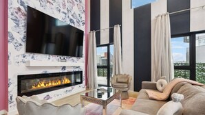 Un salon moderne doté d’une cheminée, d’un téléviseur à écran plat, d’un canapé confortable et d’un fauteuil élégant.