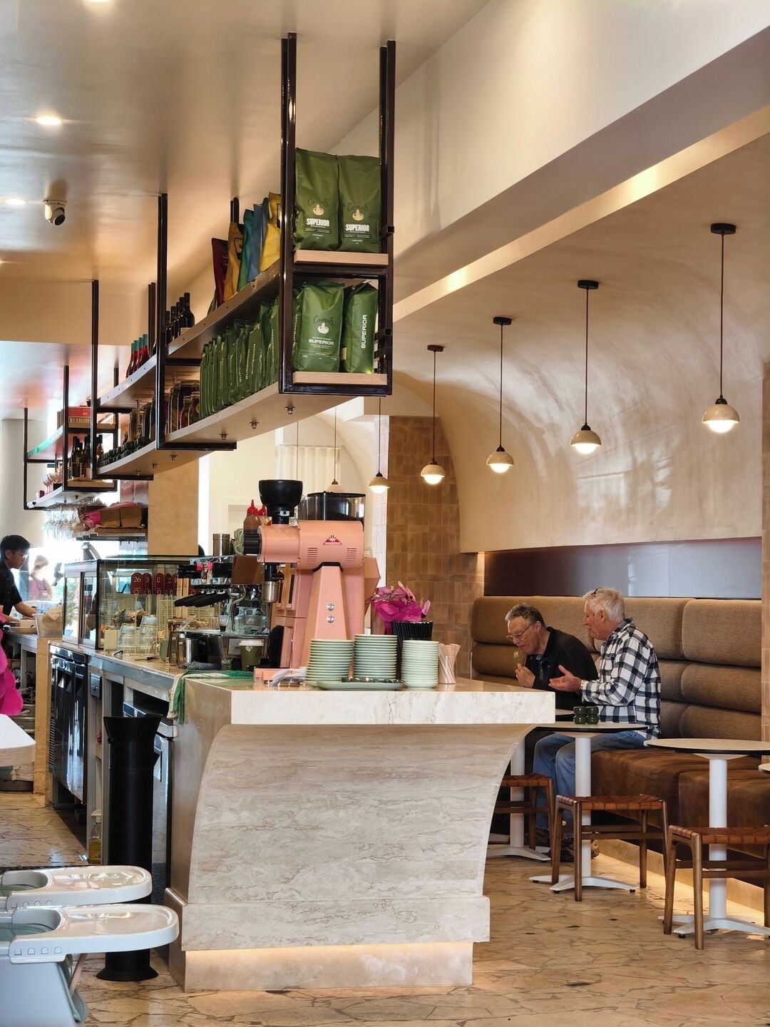A modern café interior with a central counter, seating area, and hanging lights.