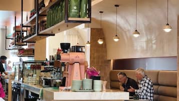 A modern café interior with a central counter, seating area, and hanging lights.