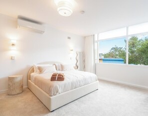 Une chambre moderne avec un grand lit, une lampe de chevet et une vue sur l’extérieur.