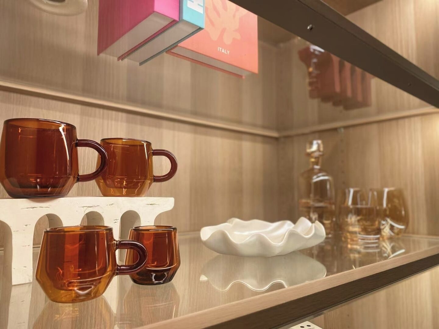 A display of amber-colored mugs on a white shelf in a hotel setting.