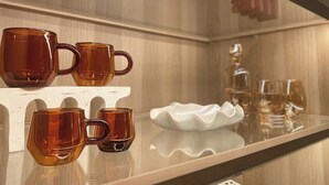 Exposição de canecas cor de âmbar sobre uma estante branca em ambiente de hotel.
