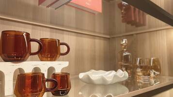 A display of amber-colored mugs on a white shelf in a hotel setting.