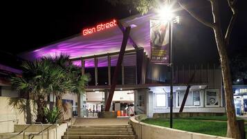 A modern building with a prominent 'Glen Street' sign, featuring a digital display and a large poster advertising 'The Alphabet of Awesome Science' event.