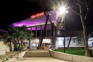 Un edificio moderno con un cartel llamativo que dice 'Glen Street', que incluye una pantalla digital y un gran cartel publicitario del evento 'The Alphabet of Awesome Science'.