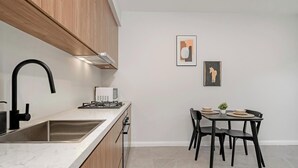 A modern kitchen with a sink, stove, and dining area with chairs and a table.