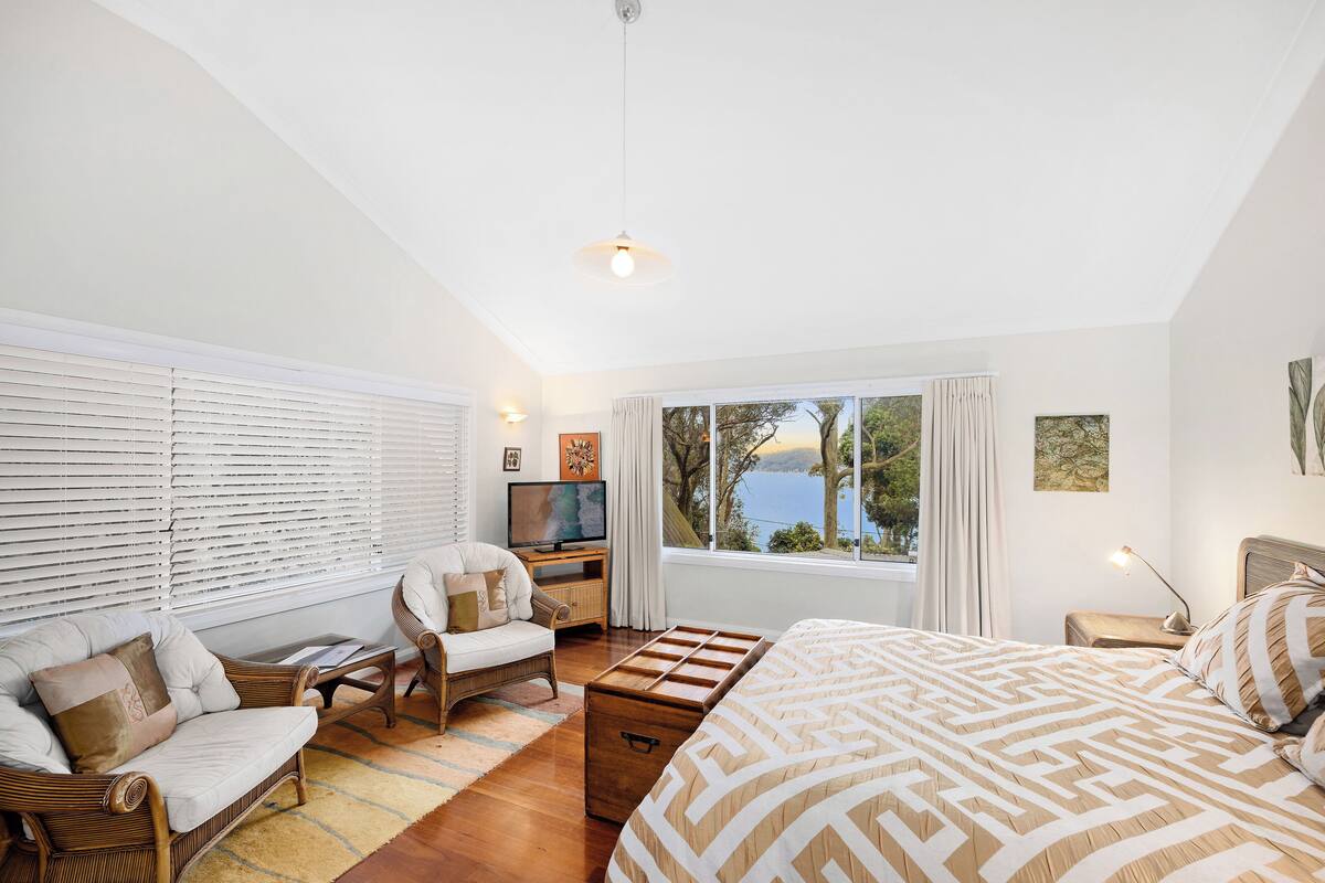 A bedroom with a bed, a sofa, a TV, and a window with a view.