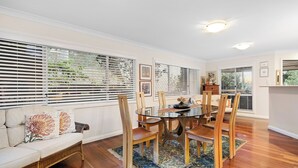 Un coin repas avec une table ronde, des chaises en bois, un canapé agrémenté de coussins décoratifs et un tapis à motifs.