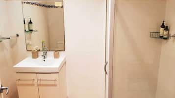A bathroom with a sink, mirror, and toiletries shelf.