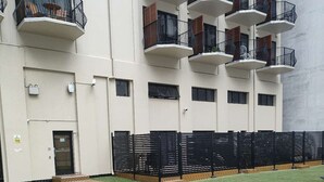 A multi-story building with balconies, a paved walkway, and artificial grass. - 3 Double 1 Single 2 Sofa Beds apartment (Auckland)