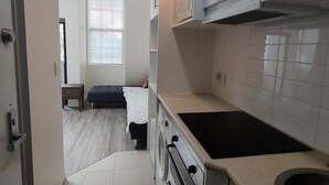 A compact kitchen with white cabinets, a built-in microwave, and a stove. - 3 Double 1 Single 2 Sofa Beds apartment (Auckland)