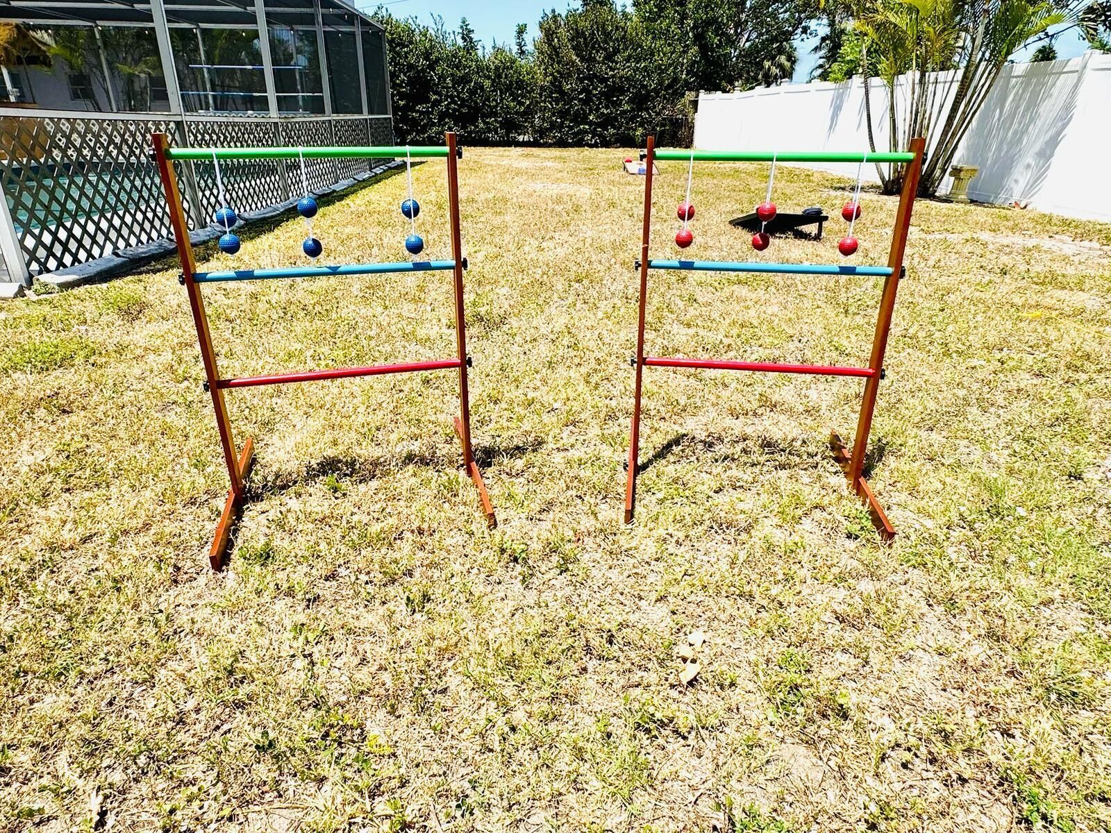 Twee metalen schommelstoelen met blauwe en rode ballen, op een gazon.