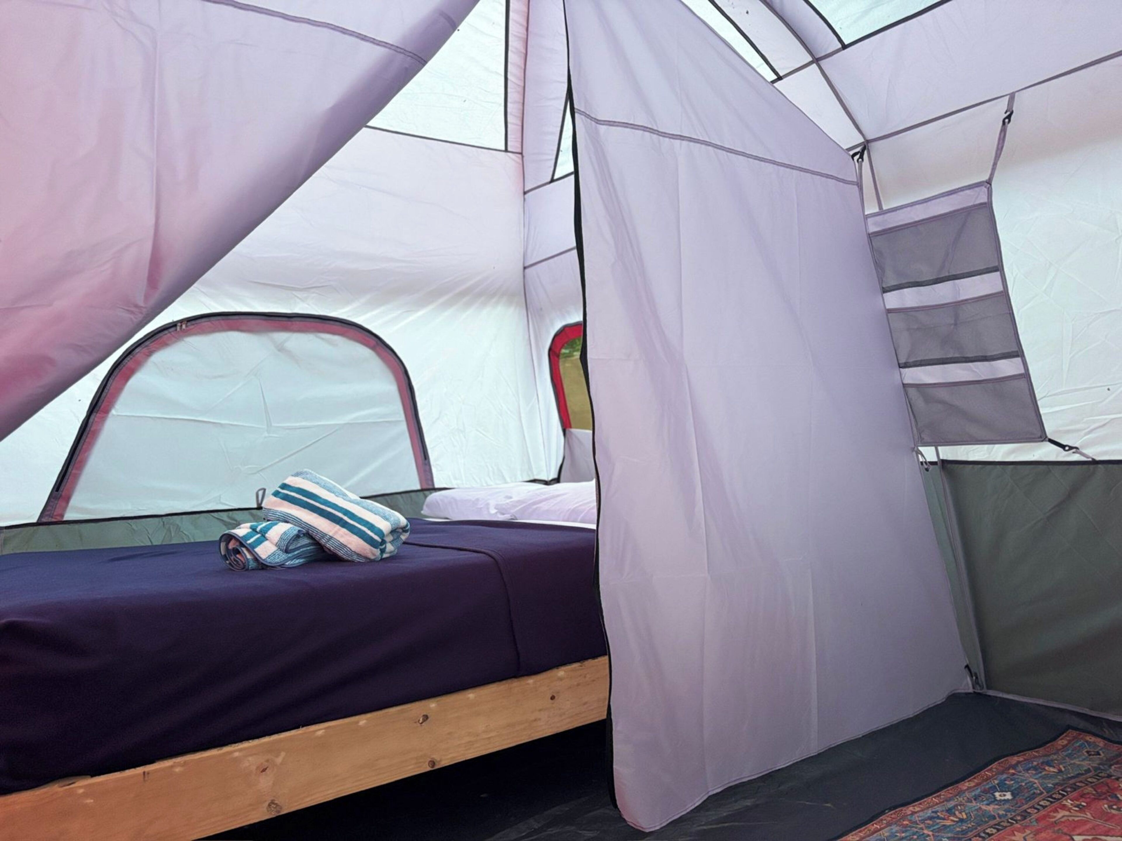 A tent with a bed, a pillow, and a small rug.