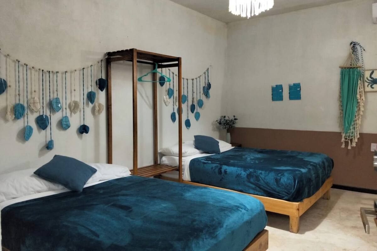 A room with two beds, a hanging chair, and a wall-mounted decoration.