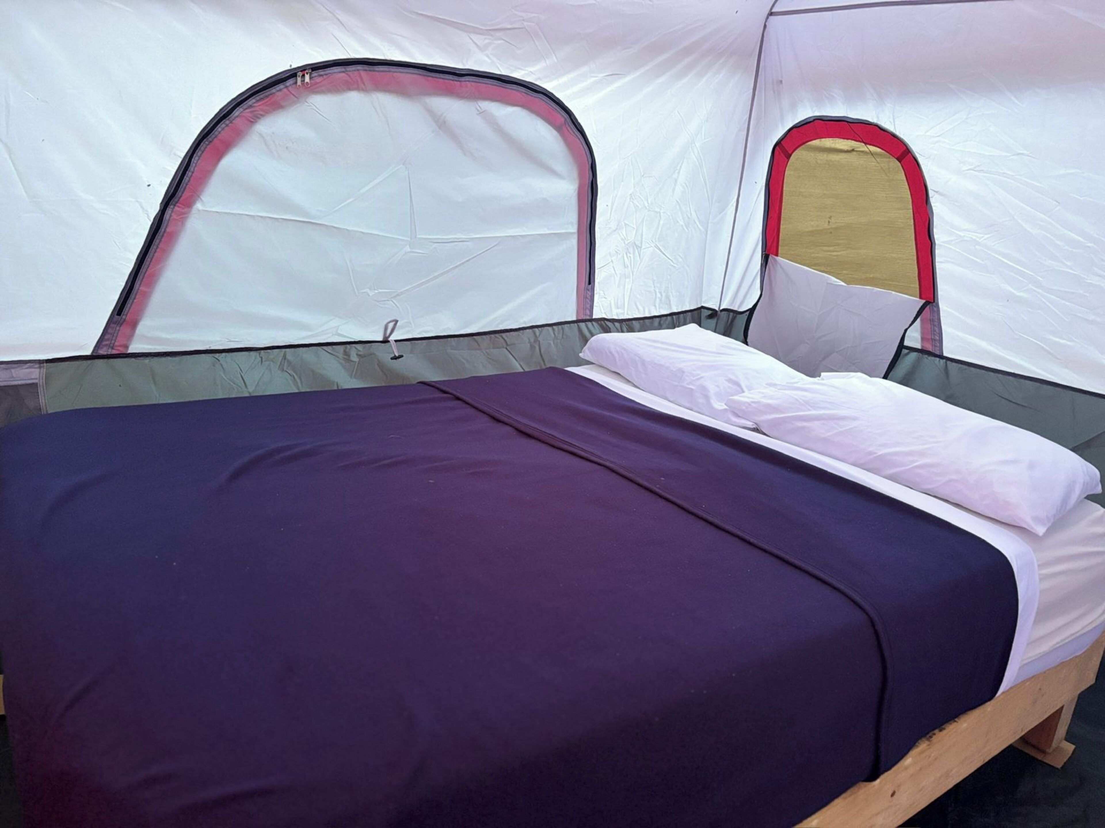 A tent with a bed, a sleeping area, and a window.