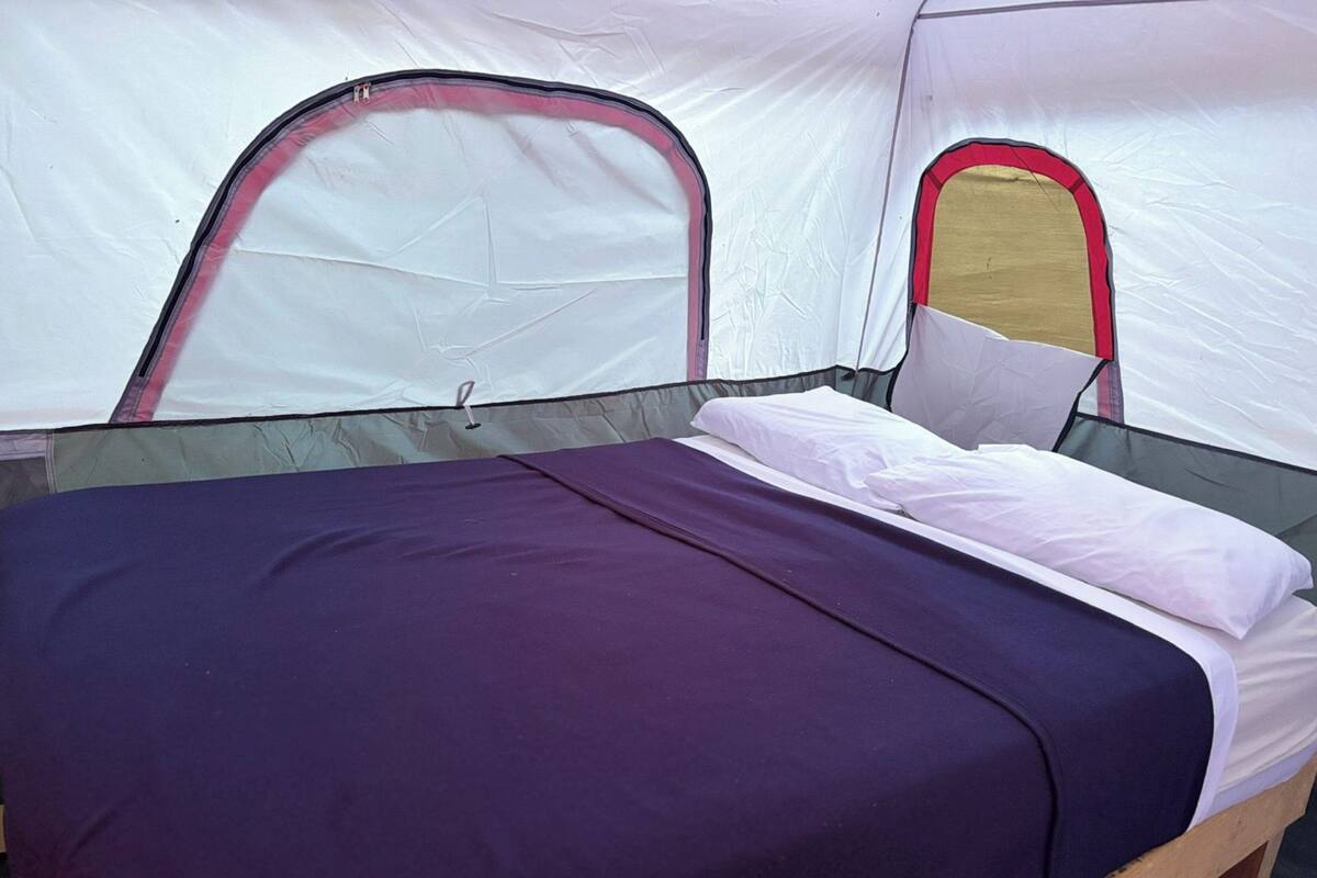A tent with a bed, a sleeping area, and a window.