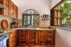 Una cocina con gabinetes de madera, encimera de granito, ventana con vistas y un microondas en la pared.