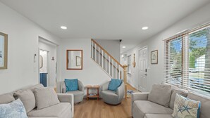 Een moderne woonkamer met twee banken, een bijzettafeltje en een trap.