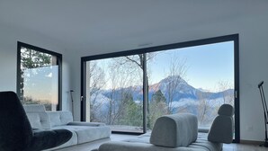 Ein modernes Wohnzimmer mit einem großen Schiebeglastür, durch die sich eine Bergblick eröffnet.