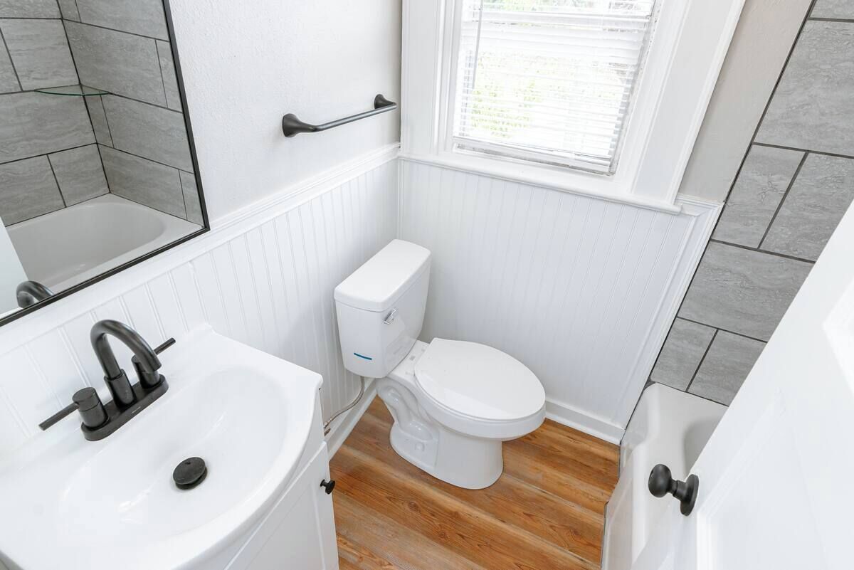 A small bathroom with a white sink, a toilet, and a window.