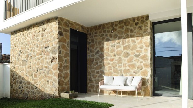A modern house with stone walls, a white balcony, and a white sofa. - Rural house with swimming pool El Huerto del Olivo, Plasenzuela, Trujillo, Cáceres (PLASENZUELA)