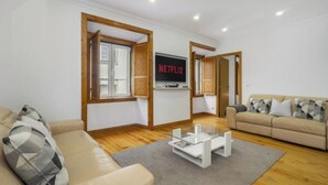 Un salon moderne avec un canapé beige, une table basse en verre et un téléviseur affichant le logo « NETFLIX ».