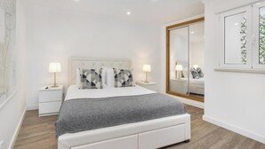 Une chambre à coucher moderne avec un lit, des tables de chevet et un grand miroir.