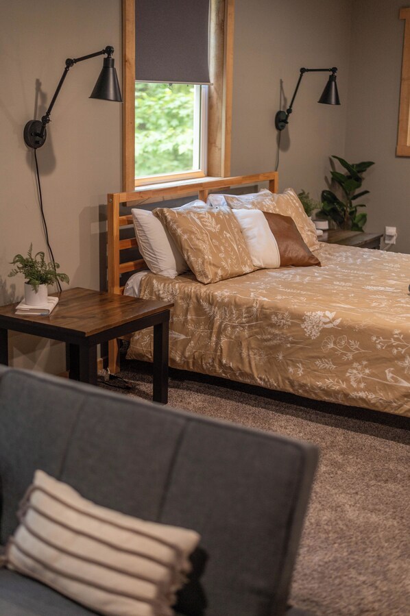 A bedroom with a bed, bedside tables, a window, and a plant.