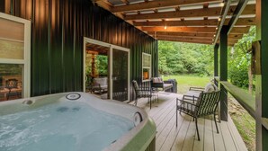 Een hottub op een houten terras, met tuinmeubilair en een overdekt gedeelte met uitzicht op de groene omgeving.