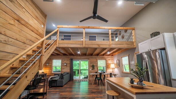 Een ruime loft-achtige kamer met een houten vloer, een entresol met balkon, een keukenhoek en een eethoek.