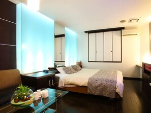 A modern hotel room with a bed, bedside table, and a glass coffee table with a plant. - HOTEL SOLA – Adults Only (Chikugo)