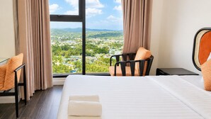 A hotel room with a large window, a bed, a desk, and a chair. - Azure Premium Apartments (Phu Quoc)