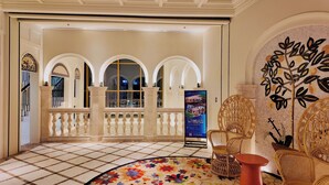 A hotel lobby with a tiled floor, a decorative round rug, and a seating area with wicker chairs. - Azure Premium Apartments (Phu Quoc)