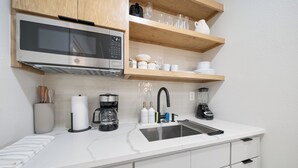 Una cucina moderna con microonde, macchina per caffè e frullatore in acciaio inossidabile sul piano di lavoro.