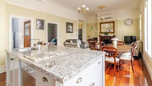 Una cocina amplia con encimeras de granito, un comedor con sillas de madera y una sala de estar con sofá y televisor.