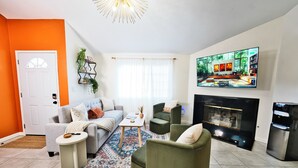 A living room with a sofa, armchairs, a coffee table, a fireplace, and a TV mounted on the wall. - Modern Hideaway - Hot Tub + 420 Friendly Patio - Near LAX, Beach + SoFi (Hawthorne)